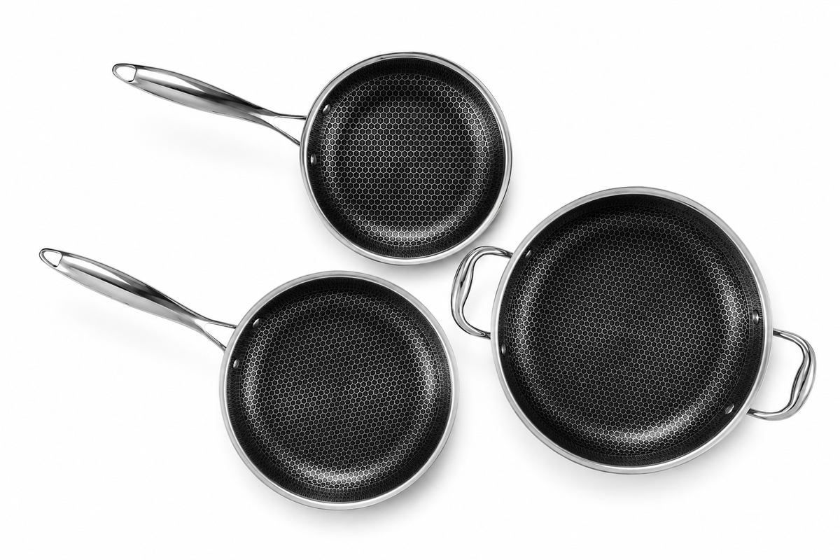 Three non-stick frying pans in different sizes with perforated black interiors and polished silver metal handles and rims, arranged on a plain white background.